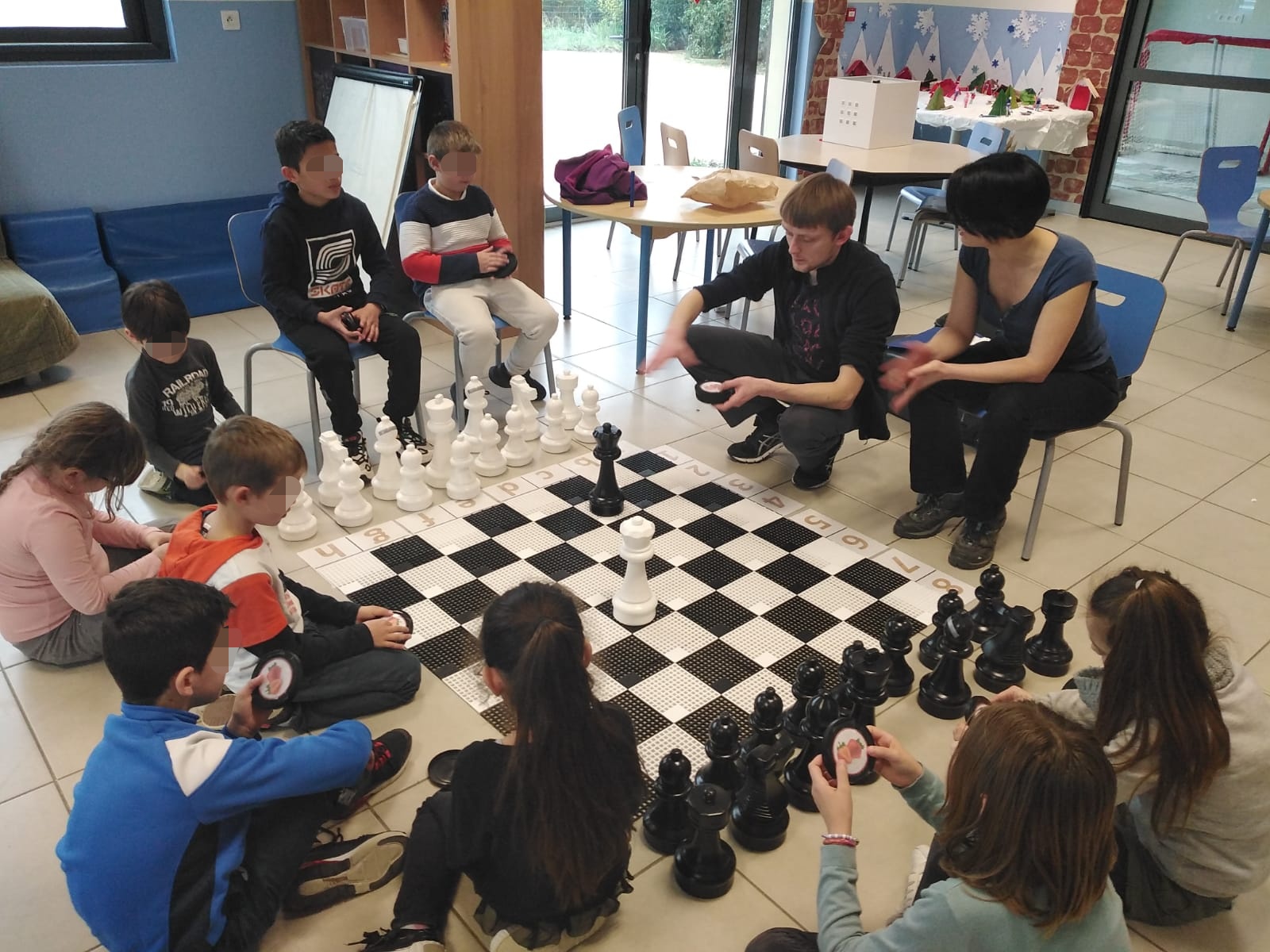 Initiation d'enfants aux échecs sur échiquier géant